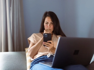 Eine junge Frau am Laptop ist besorgt und informiert sich ueber Tipps und Tricks gegen Online-Betrug.